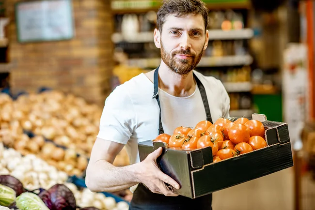 photo d'un produteur local en train de porter une caisse de fruits et légumes